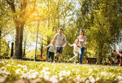 Cheerful family playing with their children's in the meadow. Family having fun in spring day.