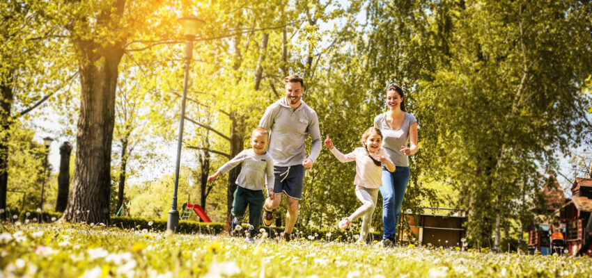 Cheerful family playing with their children's in the meadow. Family having fun in spring day.