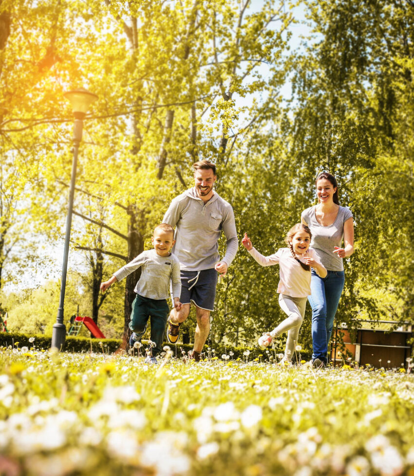Cheerful family playing with their children's in the meadow. Family having fun in spring day.